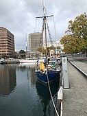 blue boat on a waterfront with some buildings as background and another white boat.