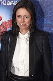 Caucasian woman with long, straight black hair dressed in black and white business attire.