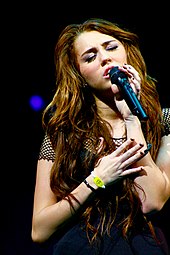 A young woman with long brown hair singing