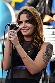 A dark-haired woman performs with a microphone