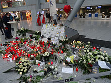 An airport interior with flowers piled against a pillar