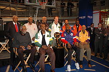 A collection of basketball players seated around the Larry O'Brien Championship Trophy