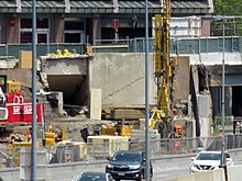 Construction work next to an urban highway, with the opening to a pedestrian tunnel visible