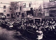 Rows of seated children and a number of standing women.