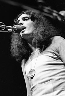 Long haired man singing into a microphone