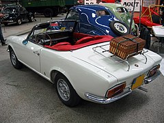 Vue arrière d'une Fiat 124 Sport Spider avec une véronique sur le coffre.