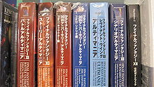 Seven thick large paperback books, each with different Japanese writing on the binding, wrapped in plastic, sitting on a shelf in a row