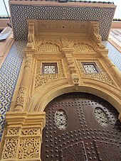 Vue en contre-plongée d'une porte d'entrée d'une demeure traditionnelle salétine, l'arcade est en pierre jaune sculptée, elle bordée de zelliges