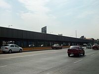 Picture of the station in the middle of Río Consolado Avenue. Several automobiles surround the station.