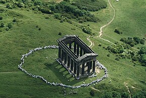 An aerial view of Penshaw Monument, surrounded by hundreds of people in white clothing