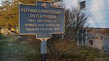 a picture of the marker with the stone church foundation visible at the side