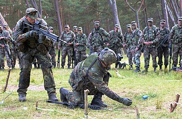 Deutsche Soldaten (Vordergrund) im Feldanzug, Tarndruck