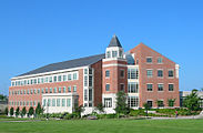 An exterior shot of a red brick building with a dark roof and white window frames.