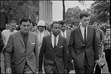 James Meredith accompanied by federal officials on either side before the columns of the Lyceum
