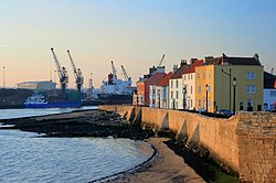 Hartlepool Town Wall: dating from the late 14th century, the limestone wall once enclosed the whole of the medieval town. The ancient houses overlook the entrance to Victoria Docks, which can be seen in the background.