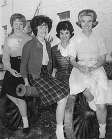 Four smiling young women posed on a cannon