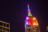 The Empire State Building illuminated by rainbow-colored lighting at night]]