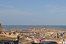 Shanty town in background behind taxis