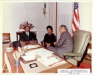 LBJ meeting with two others around the desk. The top is wooden.
