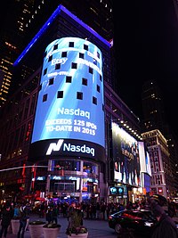 A nighttime view of Nasdaq MarketSite, which contains a large LED sign on a circular facade. There are windows in the sign.
