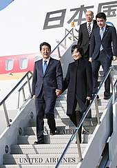 Abe disembarking from a plan with his wife, Akie Abe