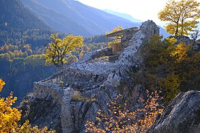 Ruines de murs. Au premier plan, un carré de mur est partiellement détruit sur deux faces.