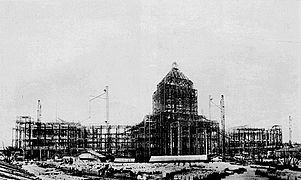 photo d'un bâtiment de très grande taille en construction. La structure métallique est bien visible et permet d'en deviner la forme finale.