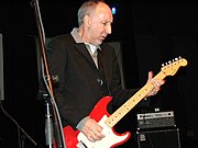 An older man playing a red guitar