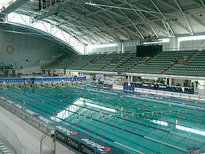 vue d'une piscine, avec dans le fond des tribunes, vides.