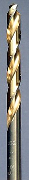 A steel colored twist drill bit with the spiral groove colored in a golden shade.