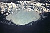 Aerial view of a large glacier, surrounded by mountains