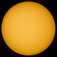 Transit of Mercury. Mercury is visible as a black dot below and to the left of center. The dark area above the center of the solar disk is a sunspot.