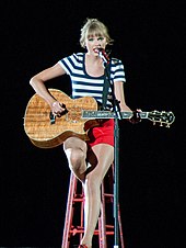 Taylor Swift on the Red Tour, playing an acoustic guitar