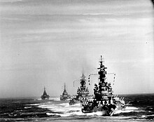 Black and white photo of four warships sailing together
