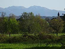 Photographie en couleurs d'une église et de montagnes au fond.