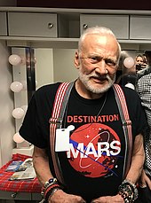 Photographie en couleur d'Aldrin arborant un tee-shirt faisant la promotion de l'exploration de Mars.