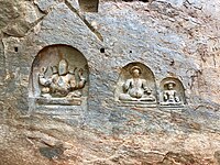 Bas-reliefs on the left side of cave temple entrance.
