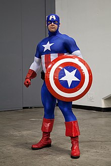Captain America tient son bouclier de même couleur que son habillement : étoile, bleu, rouge, blanc
