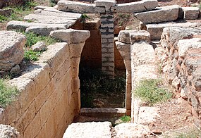 A corridor built of ashlars leads to a ruined archway