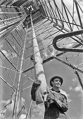 Drill string, viewed up the derrick of a roughneck and his fish tail bit on drill collar, 1938, Climax-Molybdenum Co. plant, Iowa Colony, Texas