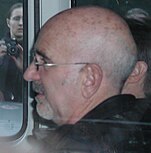 A side-shot of a bald man with glasses