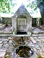 La fontaine Saint-Quirin avec son bassin rond servant aux ablutions des malades et deux statues de la Vierge et de saint Quirin dans sa niche.