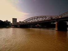 Vue d'un grand pont métallique passant au-dessus d'un fleuve.