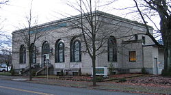 Photograph of the St. Johns Station, a rectangular, single-story building on its own block with tall, arched windows