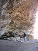 An adult standing inside a large rockshelter
