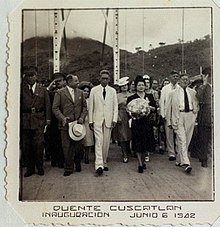 A black-and-white photograph on a stamp depicting Maximiliano Hernández Martínez and a delegation of people at the inauguration of the Cuscatlán Bridge