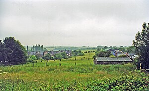 A green field with buildings in the distance