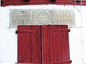 Structural lintel with a lauburu and founders' names, above traditional Basque houses in Lower Navarre, Spain