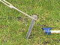 A heavy gauge pressed metal tent peg, with heavier rope and metal hatchet used as a mallet.