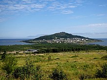 Vue d'un cap s'avançant sur la mer avec une petite ville sur l'isthme fait de bâtiments résidentiels.